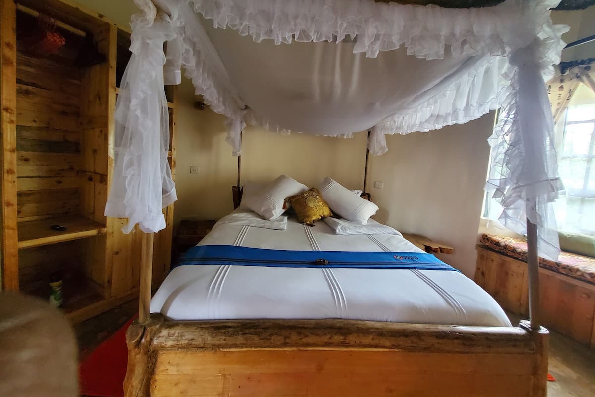 Una cama con dosel, un armario de madera y una ventana con vistas.