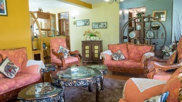 A traditional living room with ornate furniture, a glass coffee table, and a wooden cabinet.