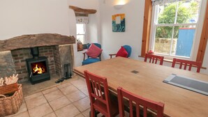 A cozy room with a fireplace, a dining table with chairs, and a large window.