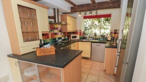 A kitchen with wooden cabinets, a tiled backsplash, and a built-in dishwasher.