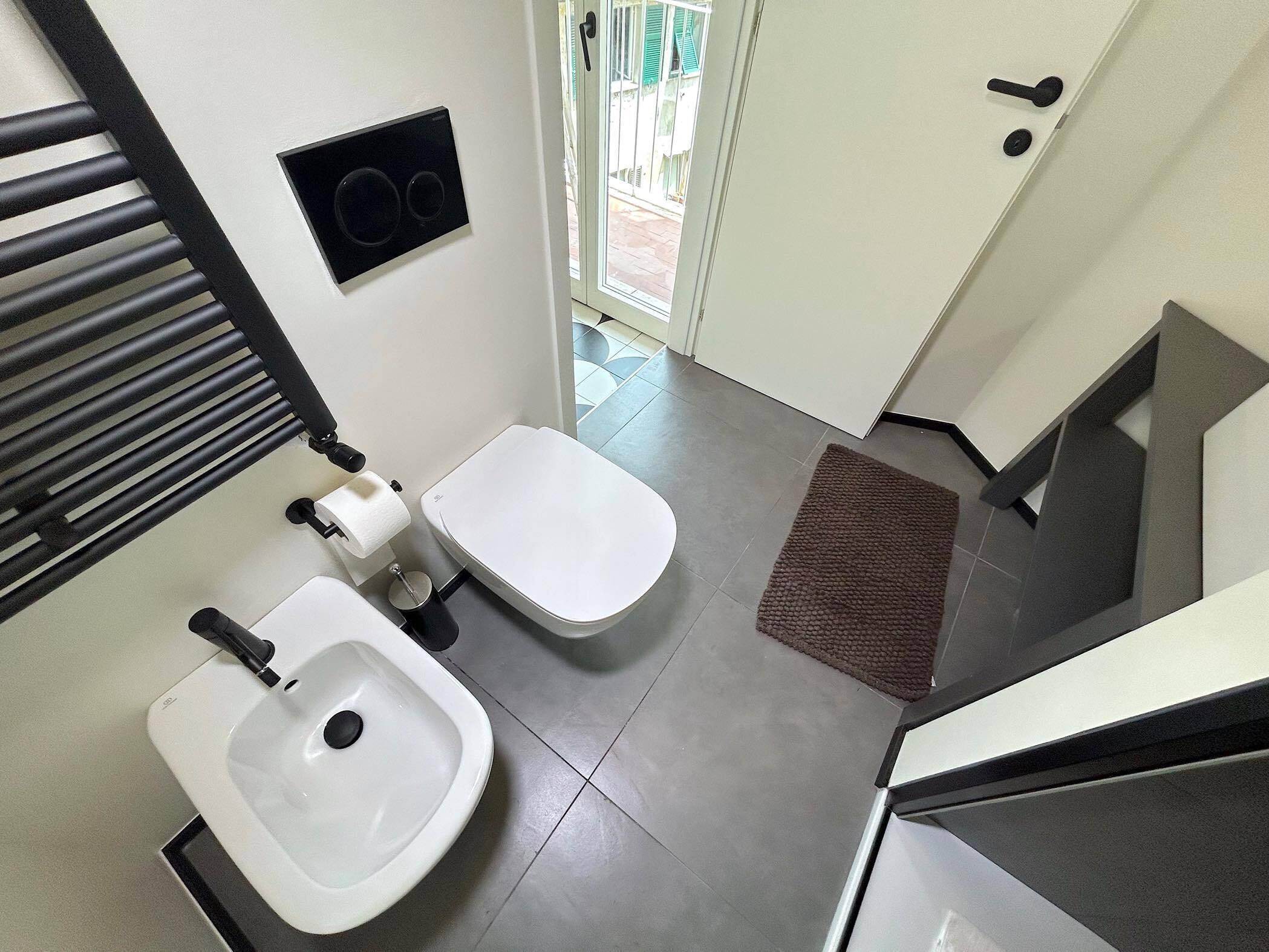 Een moderne badkamer met toilet, bidet en wastafel.