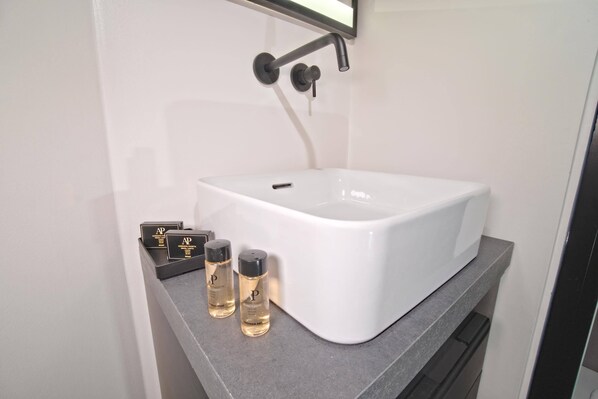 A bathroom with a white sink, a black faucet, and two bottles of lotion on the countertop.