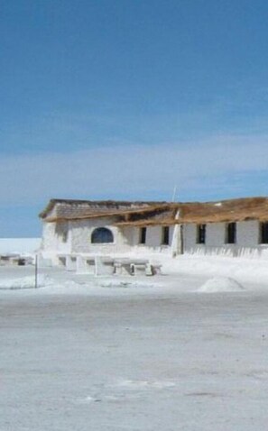 Un bâtiment blanc doté d’un toit plat et d’une seule fenêtre en arc de cercle.
