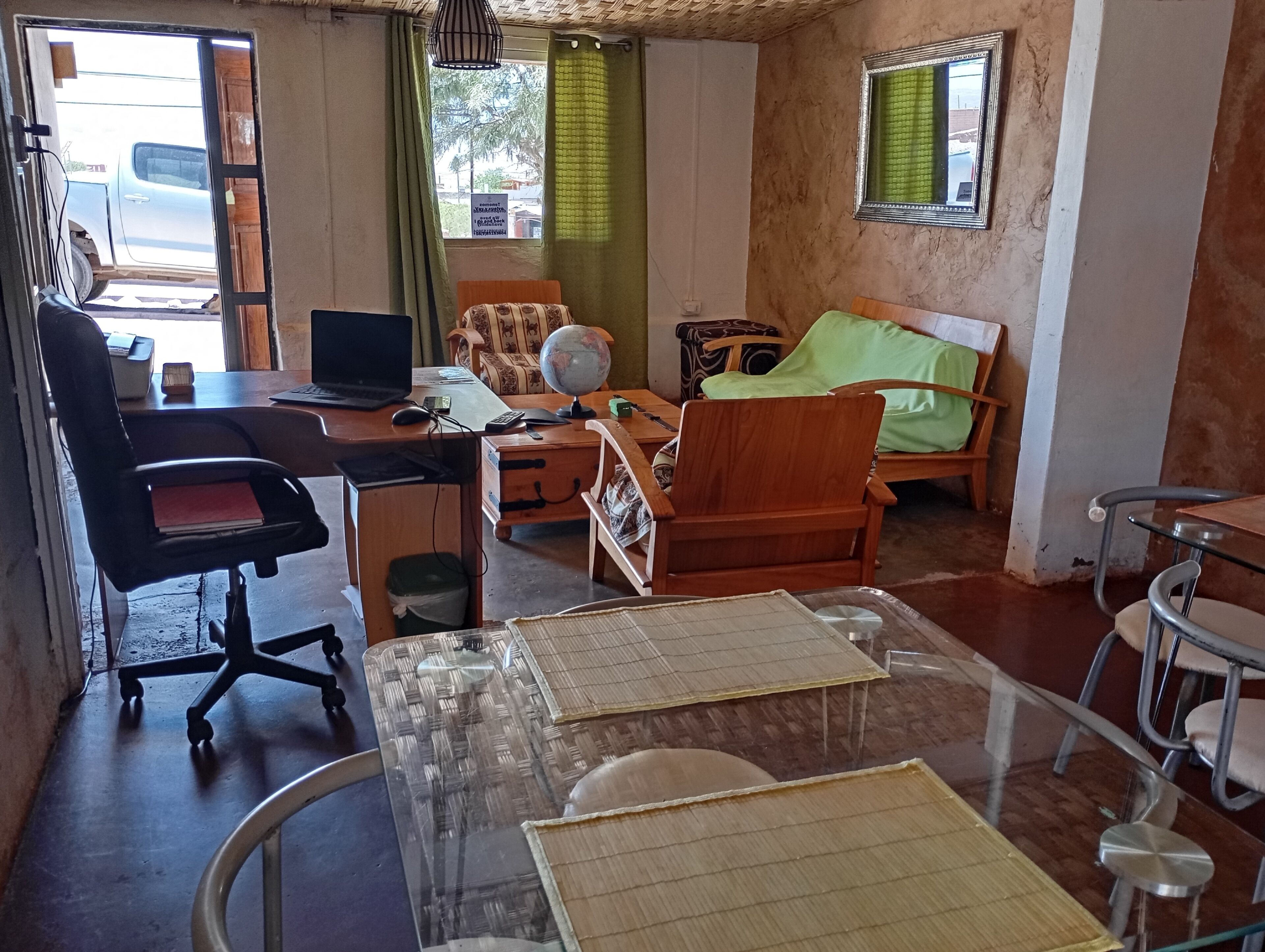 A room with a desk, office chair, bed, and a small table with a globe.