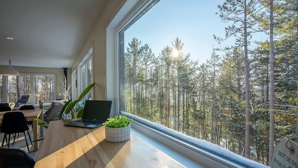 Moderni toimisto, jossa on suuri ikkuna, josta avautuu näkymä metsään.