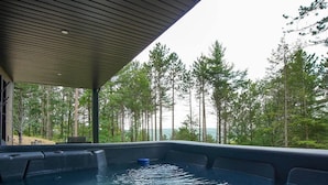 Lämmitetty poreallas, josta avautuu näkymä metsään ja vesistöön.