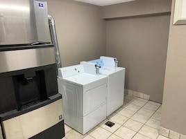Un área de lavandería con lavadora y secadora, calentador de agua y piso de baldosas.