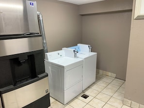A compact laundry room with a stainless steel refrigerator, a washing machine, and a dryer.