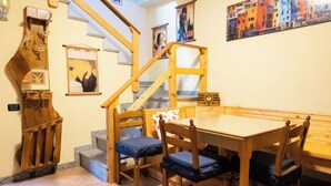 A wooden dining table with chairs, a staircase, and a wall with framed pictures. - [Apartment in the Charming Courtyard] Lake Lugano (Brusimpiano)
