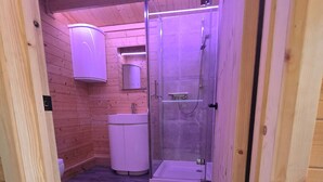 A wooden interior with a glass-enclosed shower, a white sink, and a mirror above it.