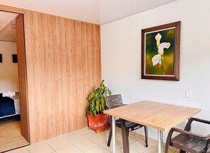 Une pièce avec une cloison en bois, une table à manger avec des chaises, une plante en pot et un tableau encadré accroché au mur.
