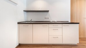 Una cocina moderna con armarios blancos, encimera negra y puerta de madera.