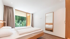 Een moderne slaapkamer met een groot raam, een houten bed en een spiegel aan de muur.