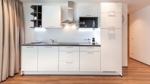 Een moderne keuken met witte kastjes, een roestvrijstalen afzuigkap en ingebouwde planken.