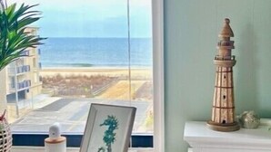 Ein Zimmer mit Meerblick, ein Schreibtisch mit Pflanze, ein gerahmtes Bild und ein Regal mit Dekoration.