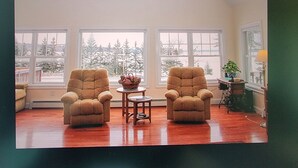 Una habitación con dos sillones, una mesita y vistas a árboles cubiertos de nieve a través de amplias ventanas.