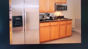 Una cocina con armarios de madera, un refrigerador de acero inoxidable, un microondas y una cafetera.