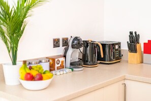 A kitchen counter with a coffee maker, toaster, and a knife block. - St Mary's Apartment (Huntingdon)
