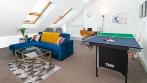 Un salon moderne avec une table de ping-pong, un canapé bleu et une table basse en verre.