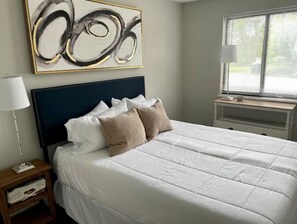 Cozy retreat with a large bed, abstract art, and natural light pouring in through the window.