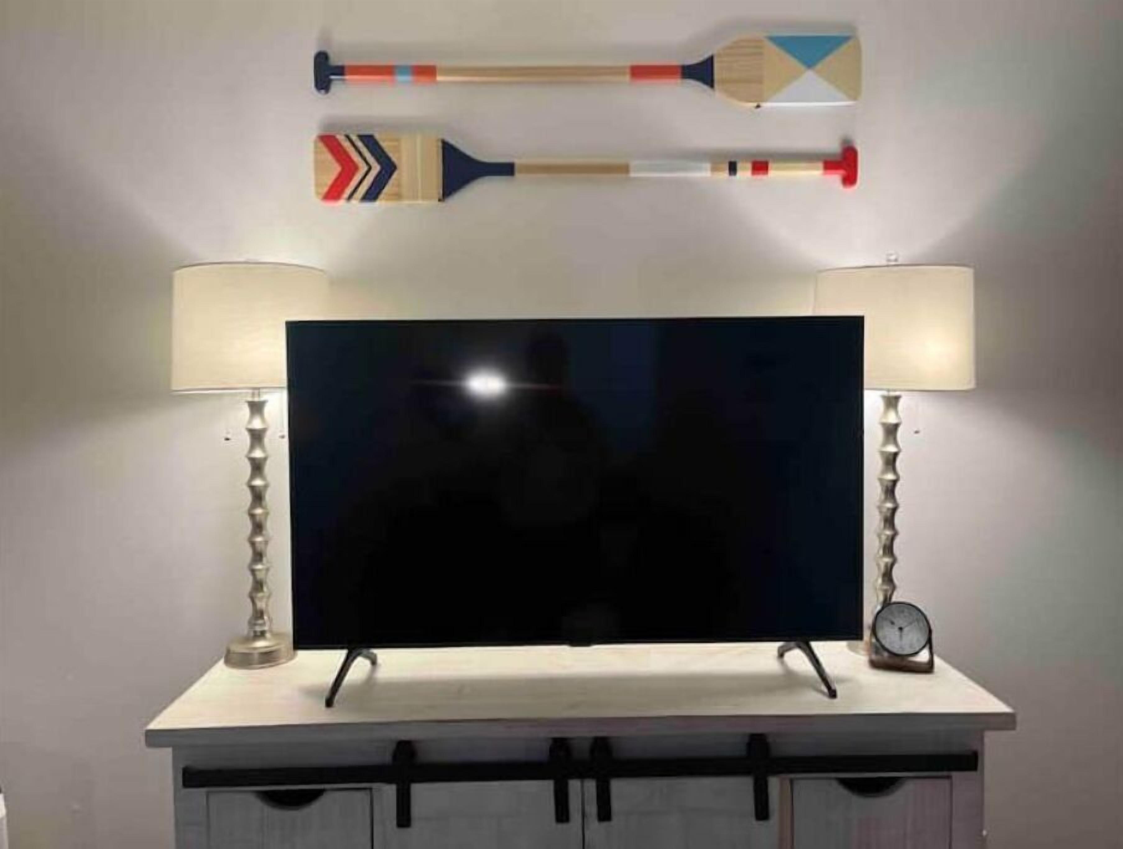 A flat-screen TV on a white cabinet with two lamps on either side.