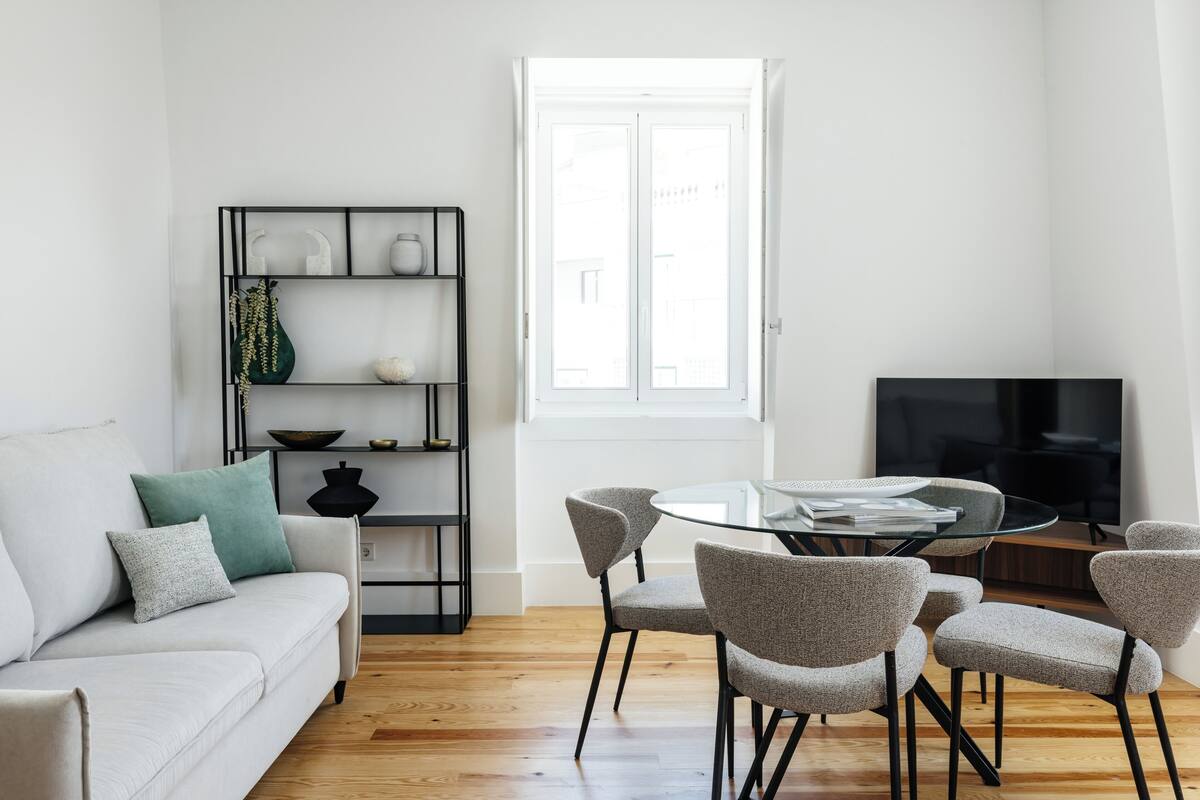 Una sala de estar moderna con un sofá, una mesa de comedor de vidrio y un televisor.