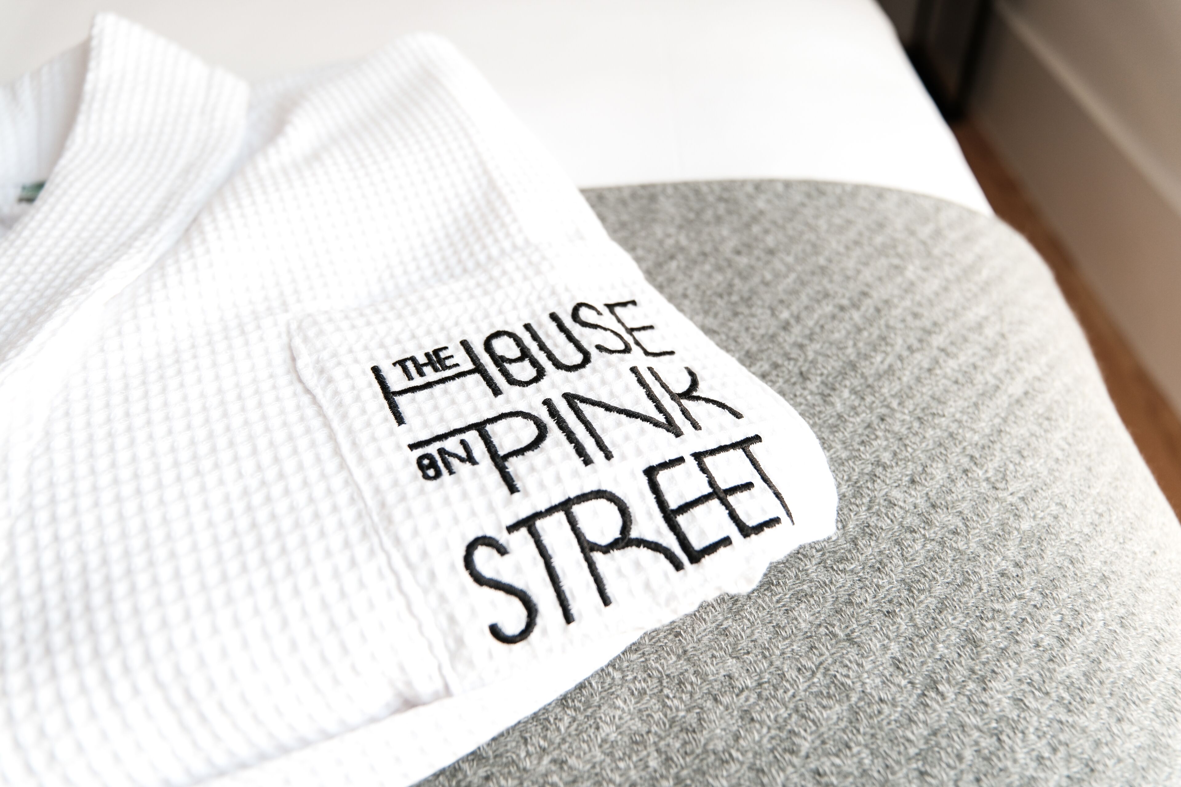 Ett vitt och grått plagg med texten ”Huset på Pink Street”.