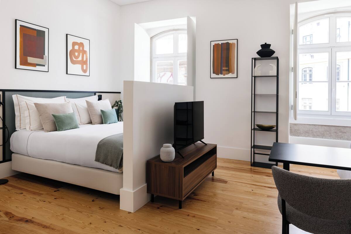 Un dormitorio moderno con cama, televisión y una pequeña mesa.