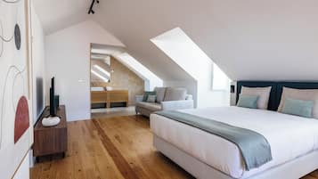 Camera da letto moderna con un letto grande, pavimento in legno, un lucernario e vista sul bagno.