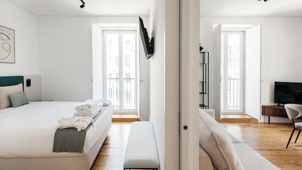 Een moderne slaapkamer met een bed, een bankje en een televisie.