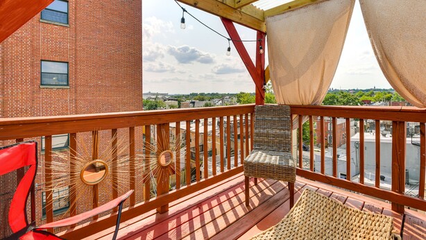 En balkon med en fletstol, en rød stol og et spejl i soludstrålingsdesign.