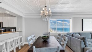 Une cuisine moderne avec des meubles blancs, une table à manger en bois et un lustre.