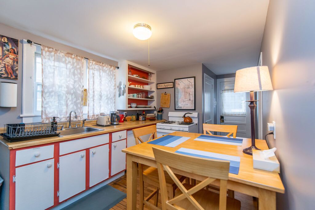 A compact kitchen with a dining area, featuring a stove, sink, and various kitchen utensils.