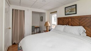 Ein Schlafzimmer mit einem großen Bett, einem Holz-Kopfteil, einem Schreibtisch mit Stuhl, einer Lampe und einem Gemälde an der Wand.