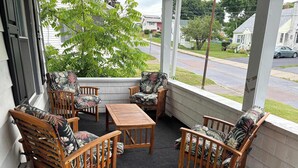 Eine überdachte Veranda mit Holzmöbeln und Blick auf die Straße.