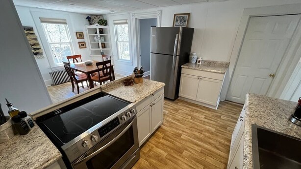 Eine moderne Küche mit einer Granit Arbeitsplatte, Edelstahlgeräten und einem Essbereich mit Holztisch und -stühlen.