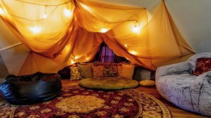A cozy room with a tent-like structure, a round rug, and a bean bag.