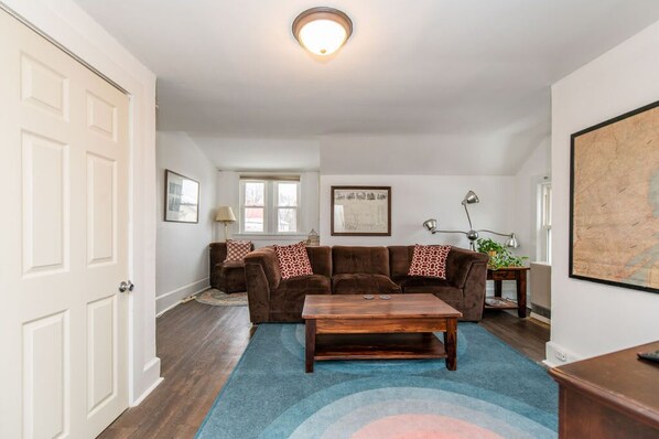 A living room with a brown sofa set, a wooden coffee table, and a blue rug.