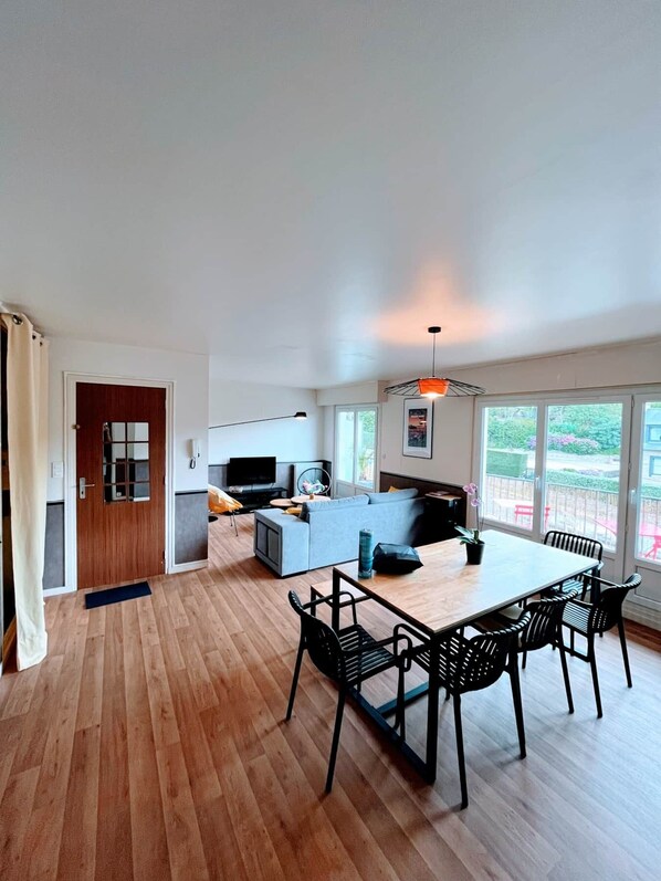 A modern living space with a dining area, kitchen, and seating area.