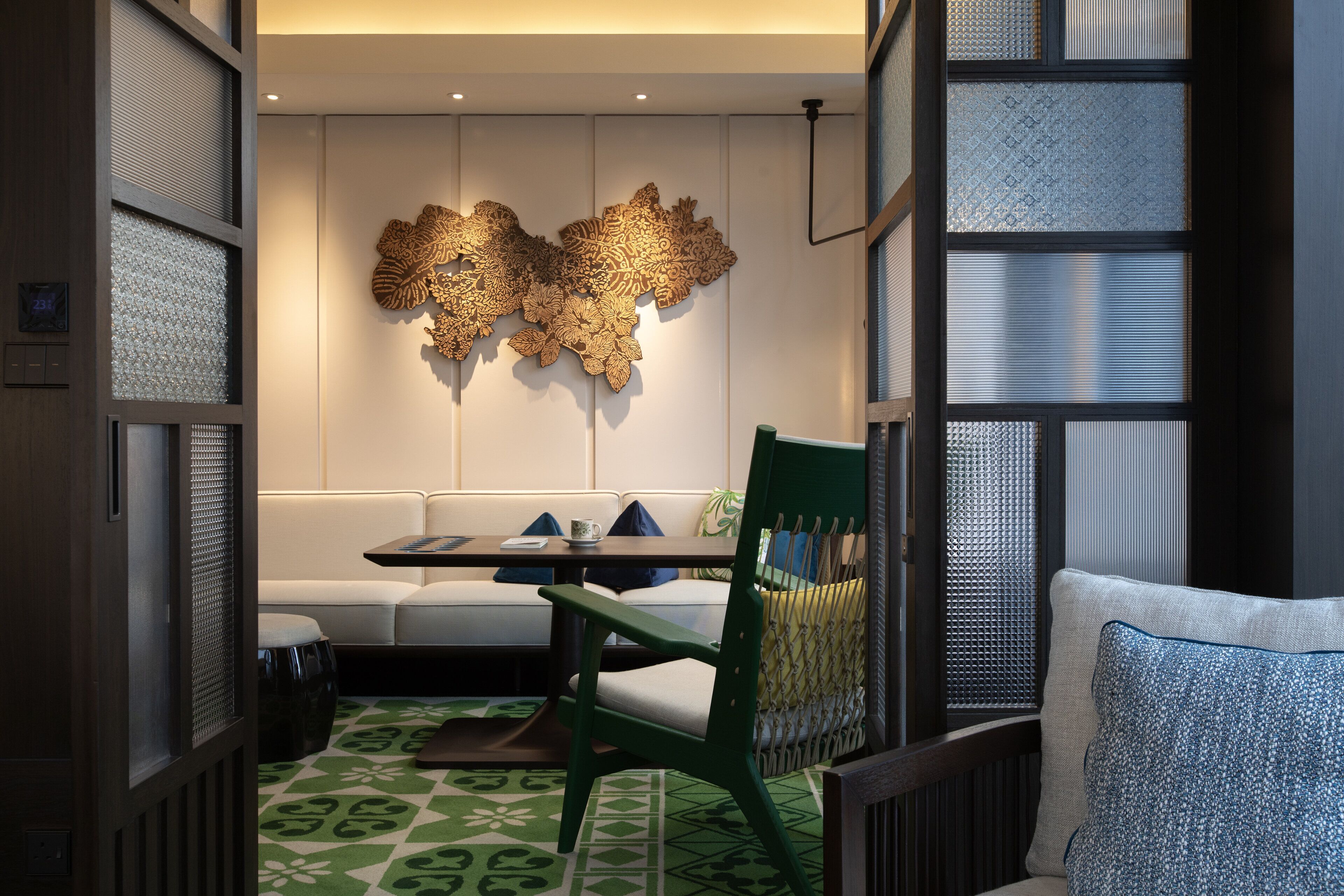 A modern interior with a sofa, a dining table, and a decorative wall piece.