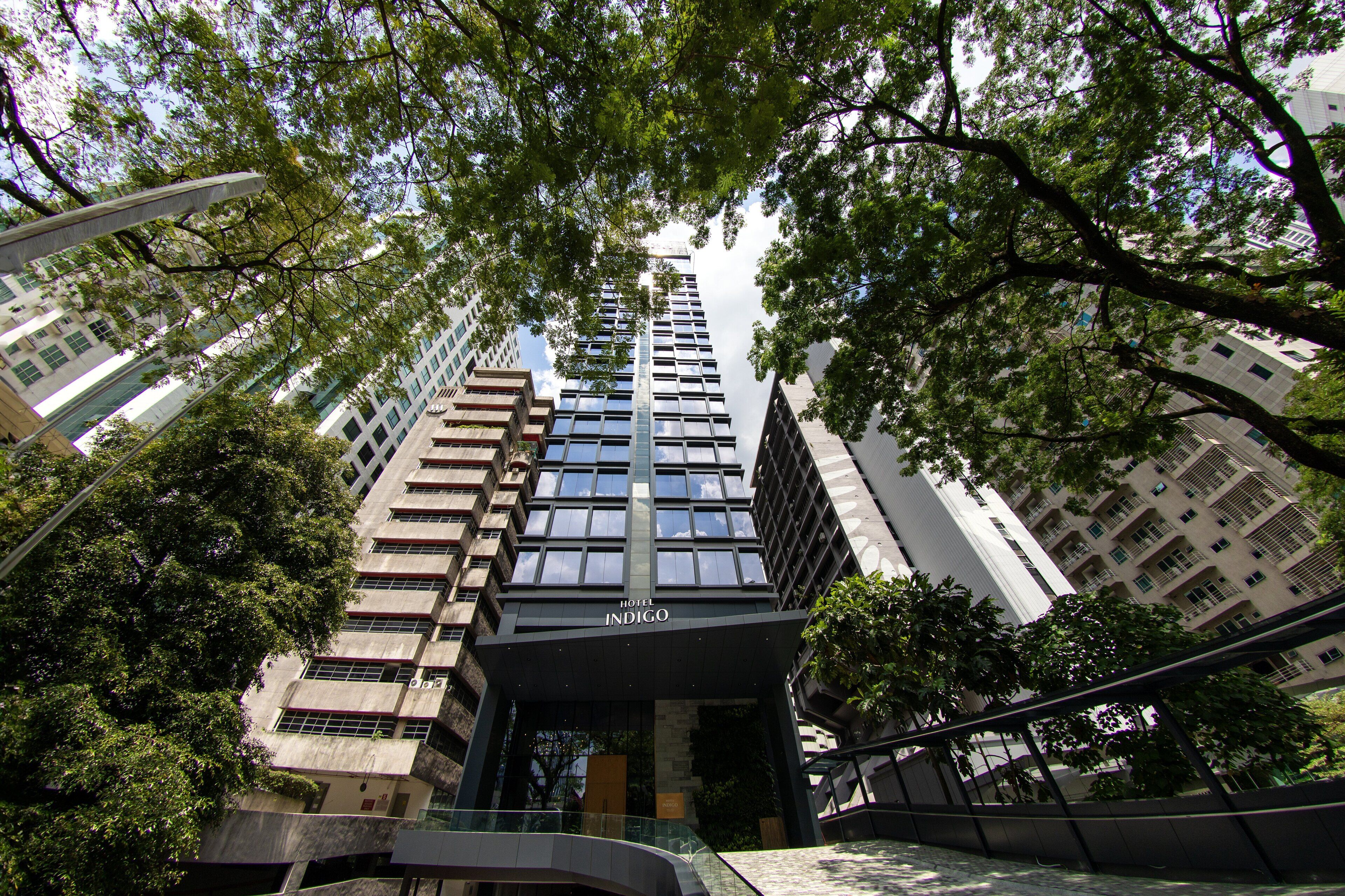 A modern hotel building with a prominent entrance and surrounding trees.