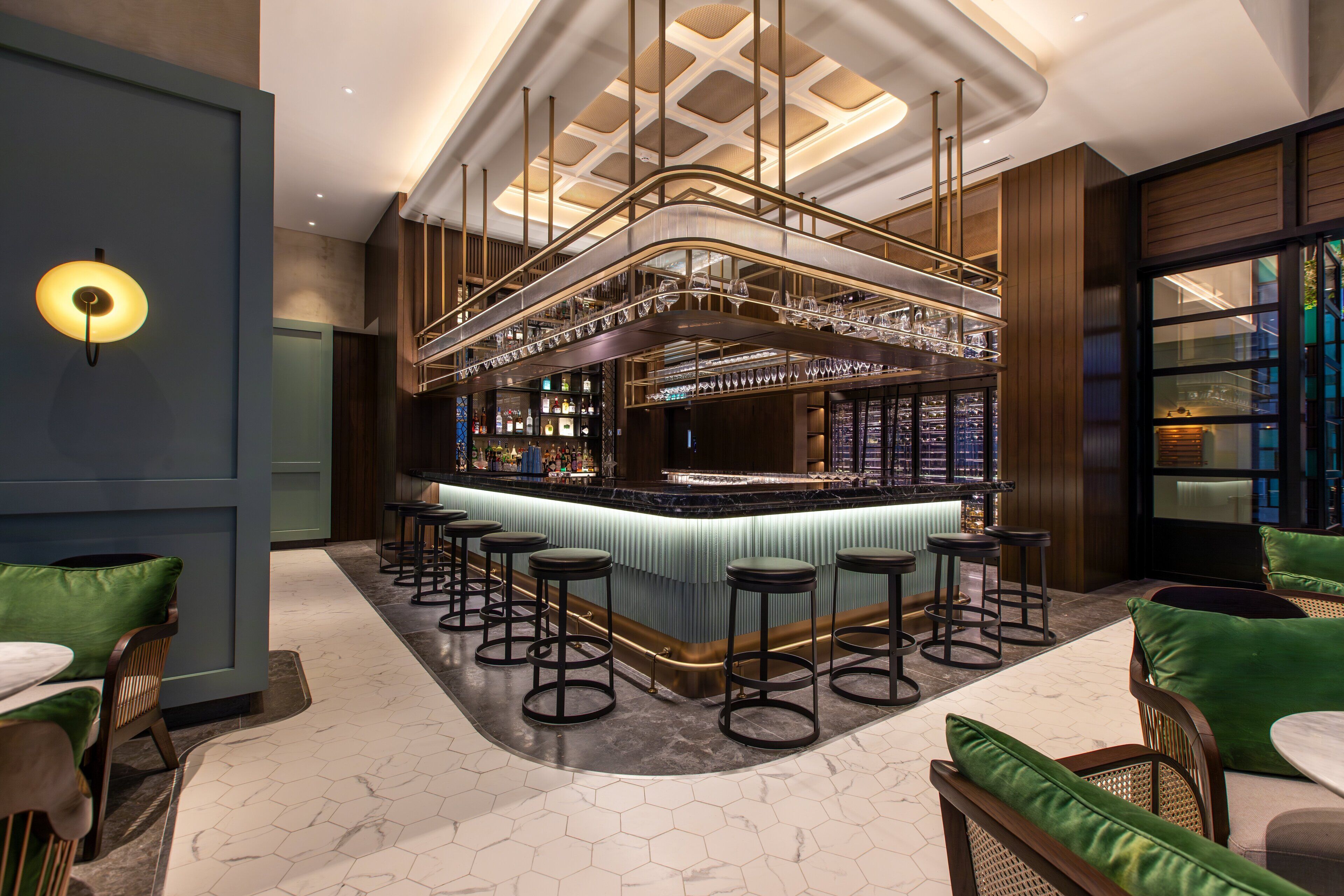 A bar area with a curved counter, multiple stools, and a variety of bottles and glasses.