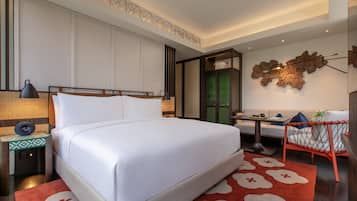 A neatly arranged hotel room with a large bed, a small desk, a chair, and a decorative wall piece.
