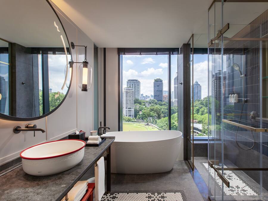 A modern bathroom with a large bathtub, a round sink, and a glass shower enclosure.