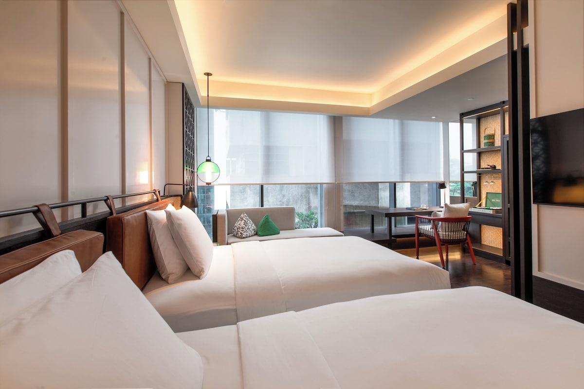 Une chambre d’hôtel moderne avec un grand lit, un bureau et un balcon offrant une vue agréable.