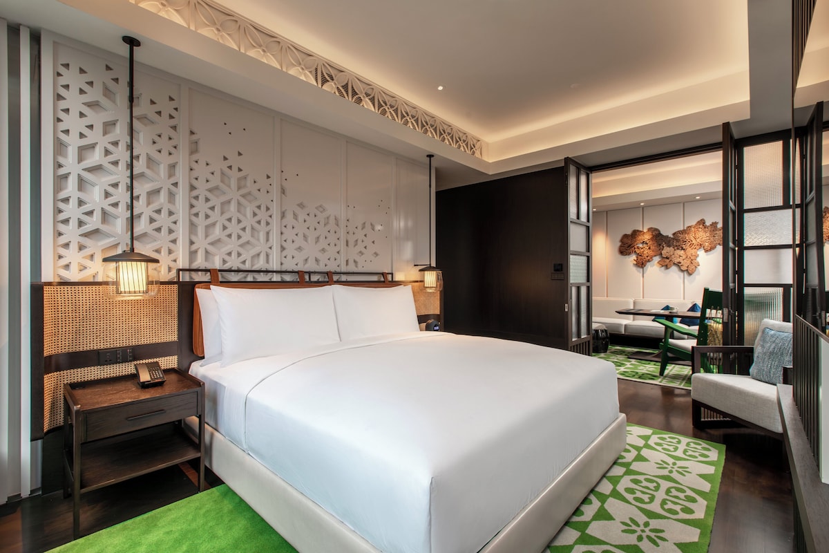 Une chambre d’hôtel moderne avec un grand lit, un bureau et un coin salon.