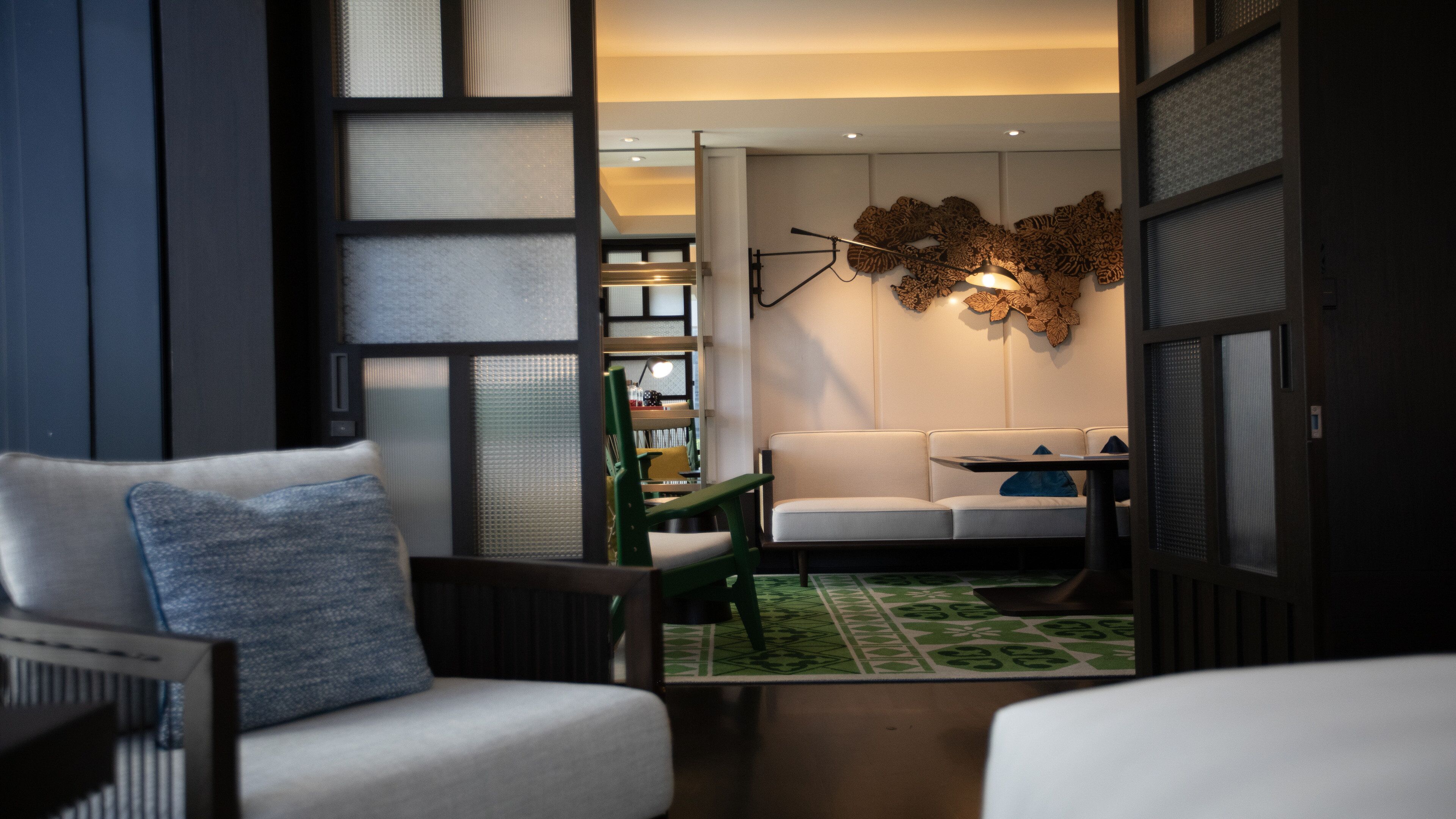 A modern living room with a sofa, a coffee table, and a green patterned rug.