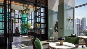 Un intérieur moderne avec un coin salon, de grandes fenêtres et une vue sur le paysage urbain.