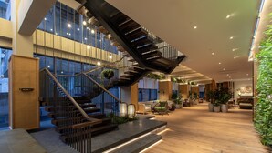 Un intérieur moderne agrémenté d’un escalier en bois, de coins salon et de plantes en pot.