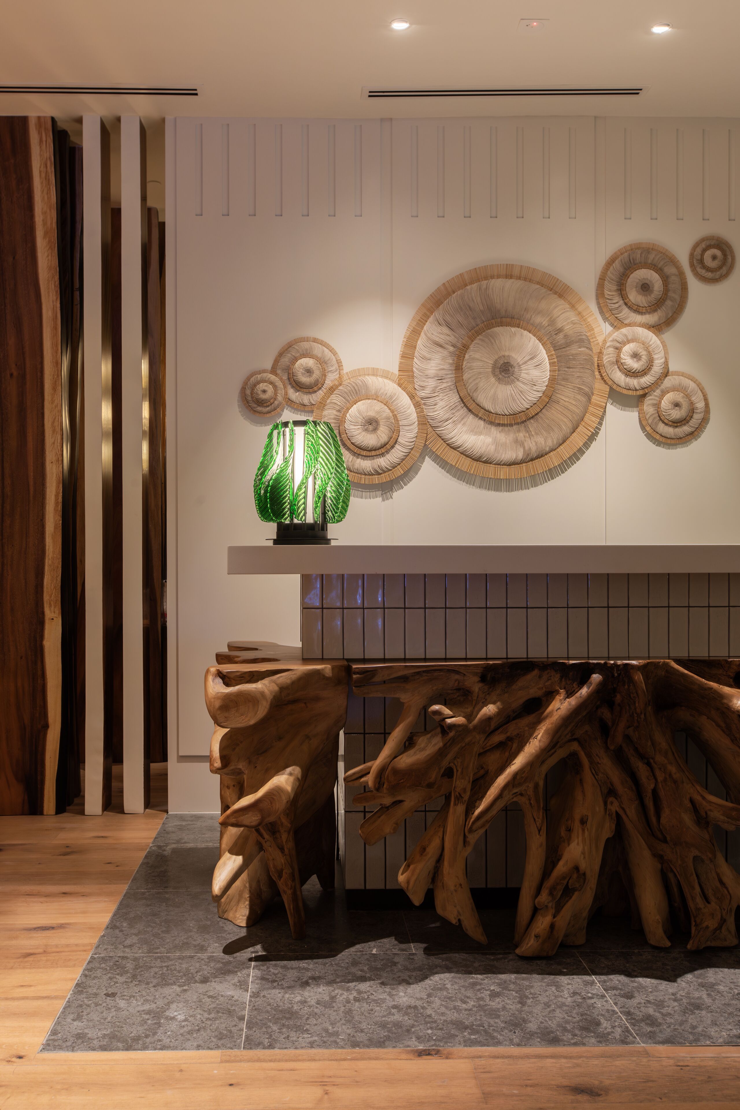 A modern interior with a wooden art piece, a unique wall decor, and a textured floor.